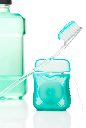 a whitening kit with toothbrush with toothpaste on it leaning against floss container and mouthwash in the back