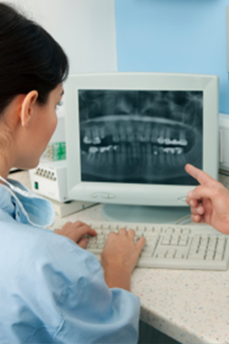 A dentist looking at a digital x-ray image of a patient's teeth